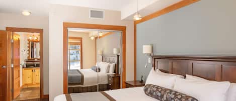 A hotel room with a large bed, a wooden headboard, a bedside table, and a mirror.