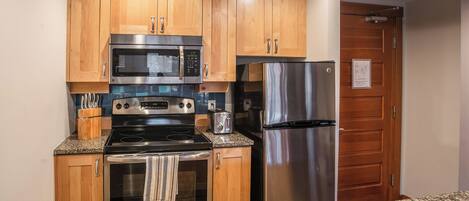 A kitchen with wooden cabinets, stainless steel appliances, granite countertops, and a stainless steel sink.