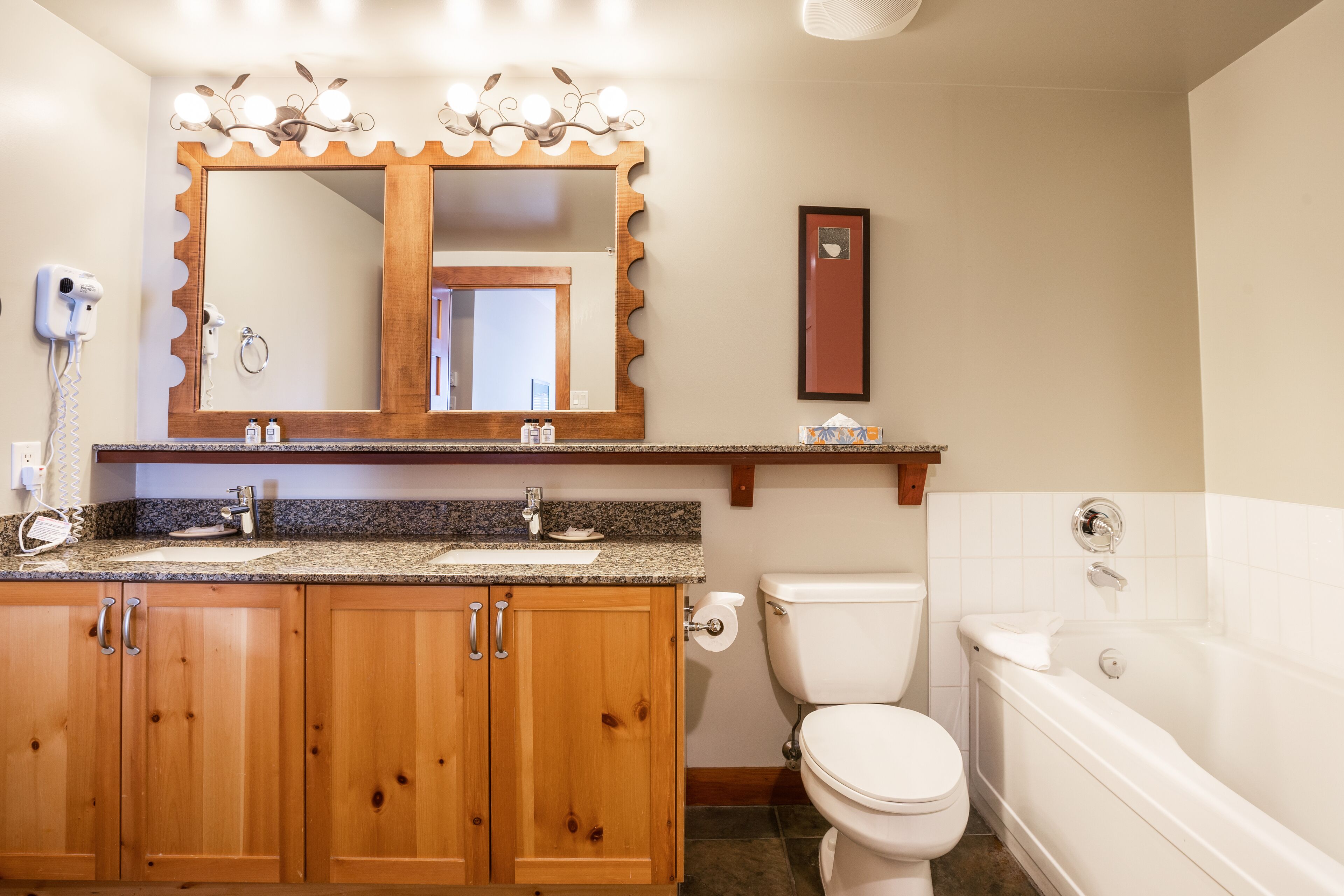 Une salle de bain avec des meubles en bois, un lavabo, des toilettes et une baignoire.