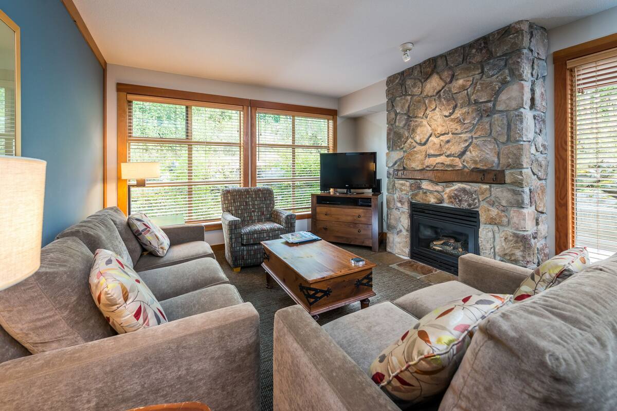 A living room with a stone fireplace, a television, and a sofa set.