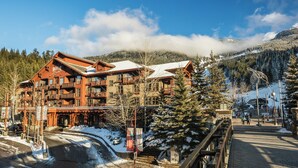 A multi-story hotel with balconies, a ski slope in the background, and a snowy landscape. - Legends Whistler, by Lodging Ovations (Whistler)