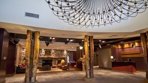 A lobby with a stone fireplace, seating area, and a reception desk. - Legends Whistler, by Lodging Ovations (Whistler)