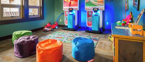 A children's play area with two Wii gaming stations, colorful bean bags, and a toy car.