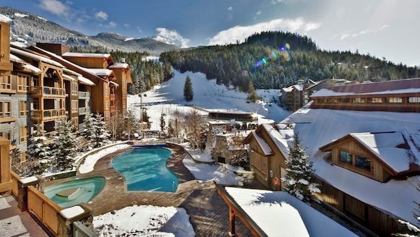 A resort with a pool, wooden buildings, and a snowy mountain backdrop. - Legends Whistler, by Lodging Ovations (Whistler)