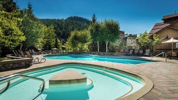 Een buitenzwembad, ligstoelen bij het zwembad