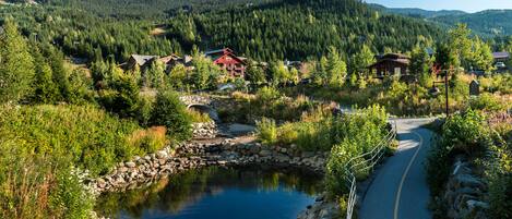 A mountain lodge with a pond, surrounded by dense forest and mountains.