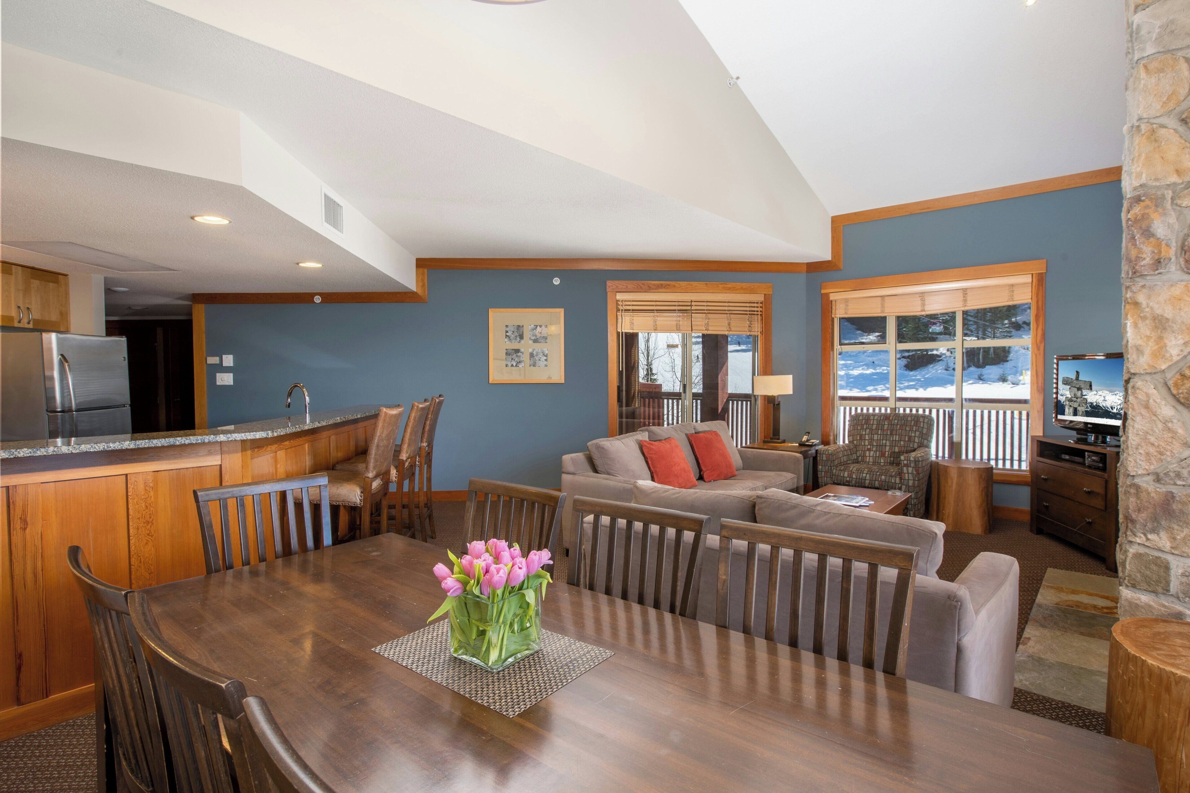 A spacious living area with a dining table, a sofa, and a kitchen area with a refrigerator.