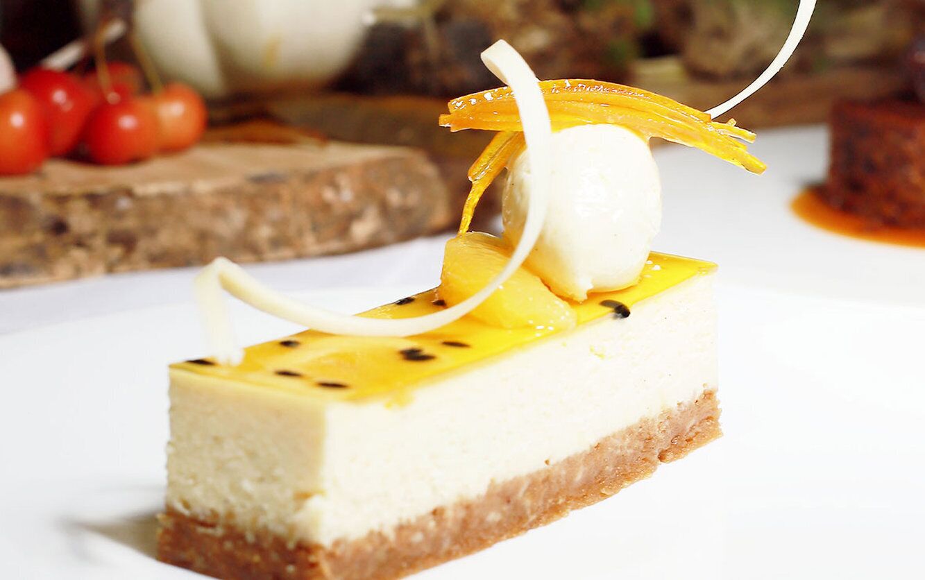 En bit cheesecake med frukt och en dekorativ garnering.
