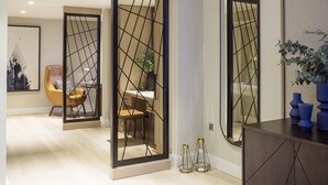 A modern interior with a wooden floor, a dining area with a table and chairs, and a large mirror with a geometric frame. - The Lowry Hotel Manchester (Manchester)