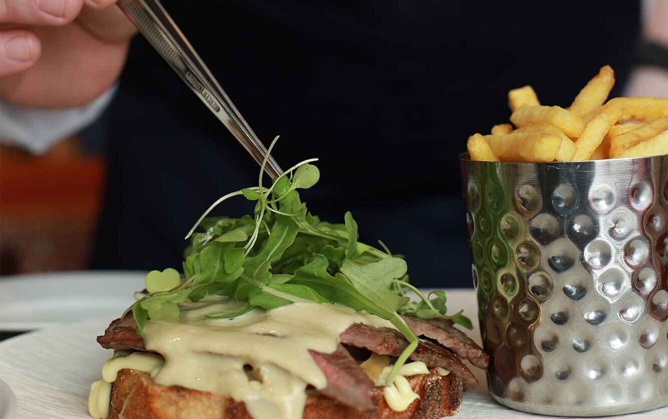 Un sándwich con vegetales y una porción de papas fritas.