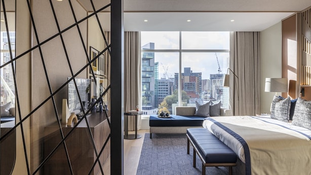 A modern hotel room with a large bed, a bench, a view of the cityscape, and a geometric wall design. - The Lowry Hotel Manchester (Manchester)