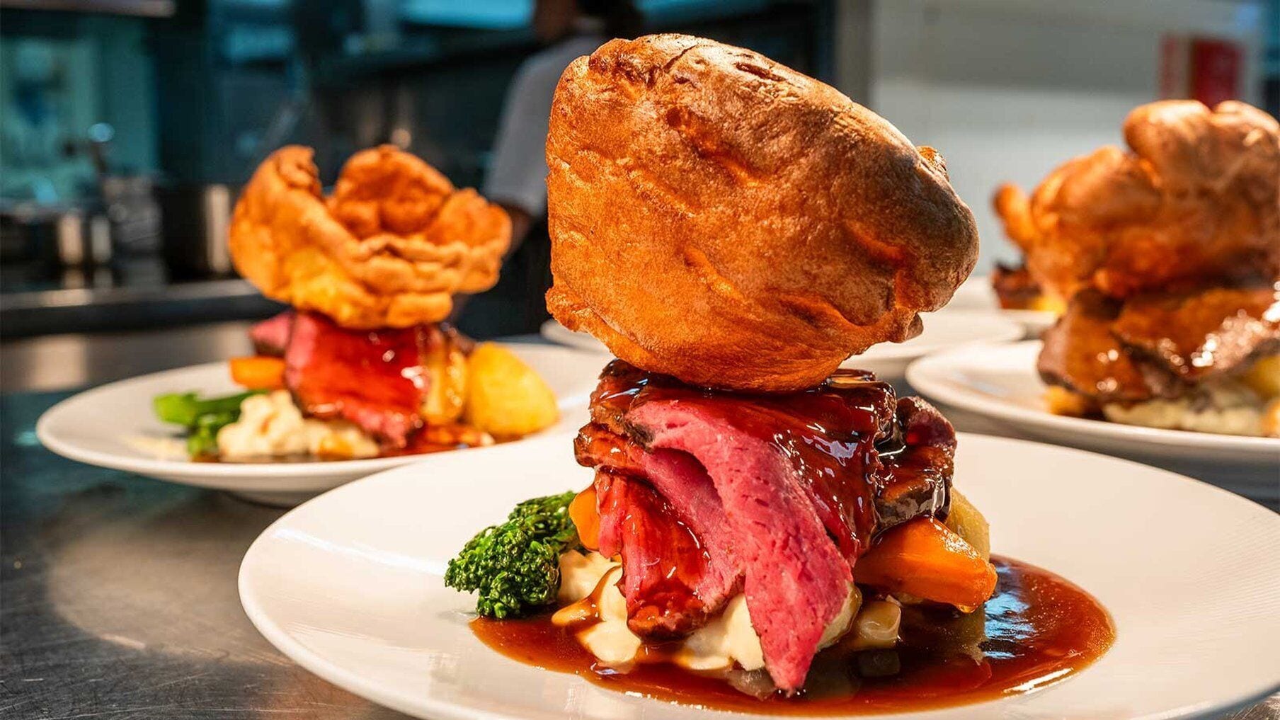 A dish with Yorkshire pudding, roast beef, and vegetables on a plate.
