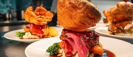 A dish with Yorkshire pudding, roast beef, and vegetables on a plate.
