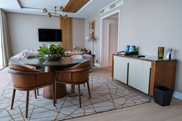 A modern living room with a round dining table, brown leather chairs, a glass coffee table, and a large potted plant.