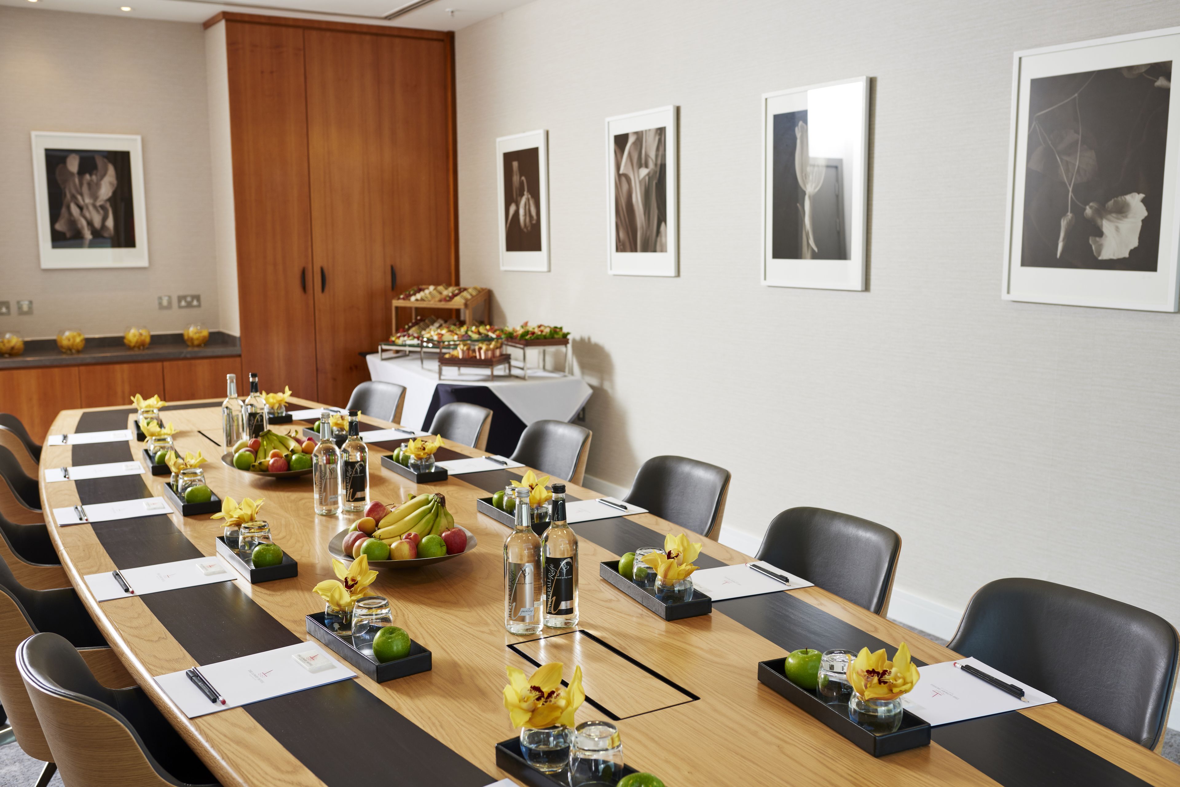 A conference room with a long table, chairs, and framed pictures on the wall.