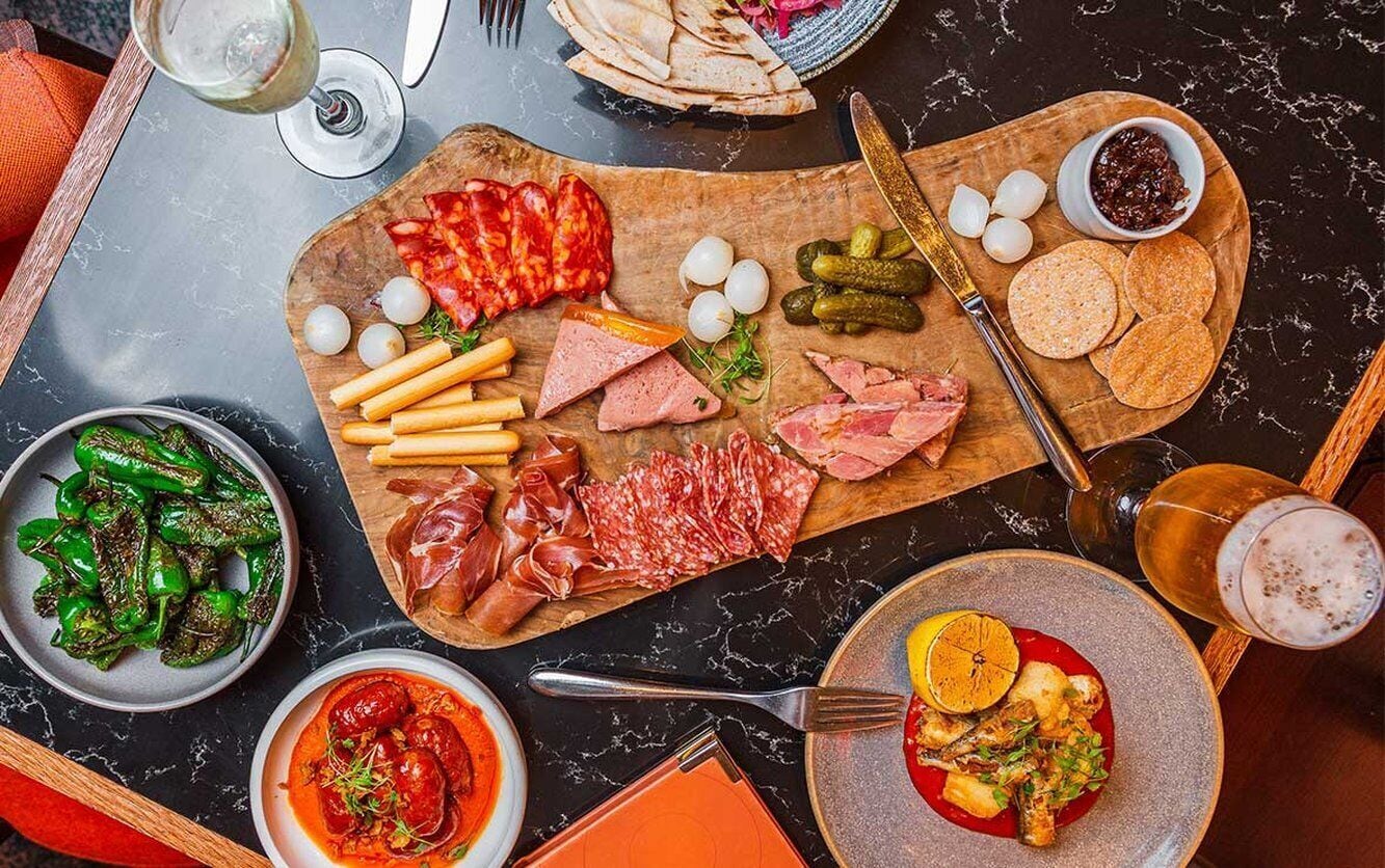 A charcuterie board with various meats, cheeses, and crackers on a wooden board.