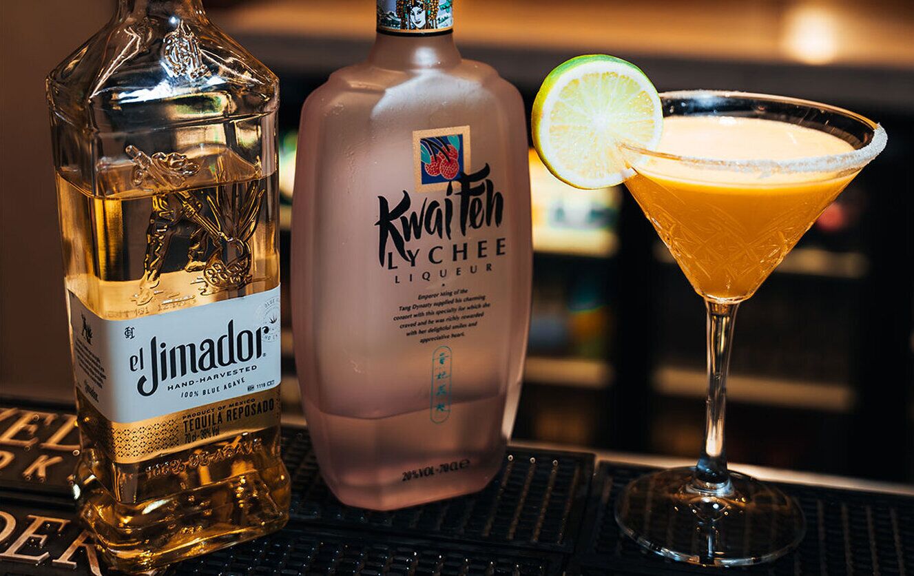 En flaske el Jimador tequila og en flaske Kwai Teh liqueur med et cocktailglas.