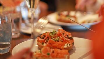 A close-up of a plate with a food item, possibly a sandwich or appetizer, garnished with green herbs and thinly sliced onions.