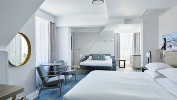 Une chambre d’hôtel avec un grand lit, un bureau, une chaise et un miroir rond.