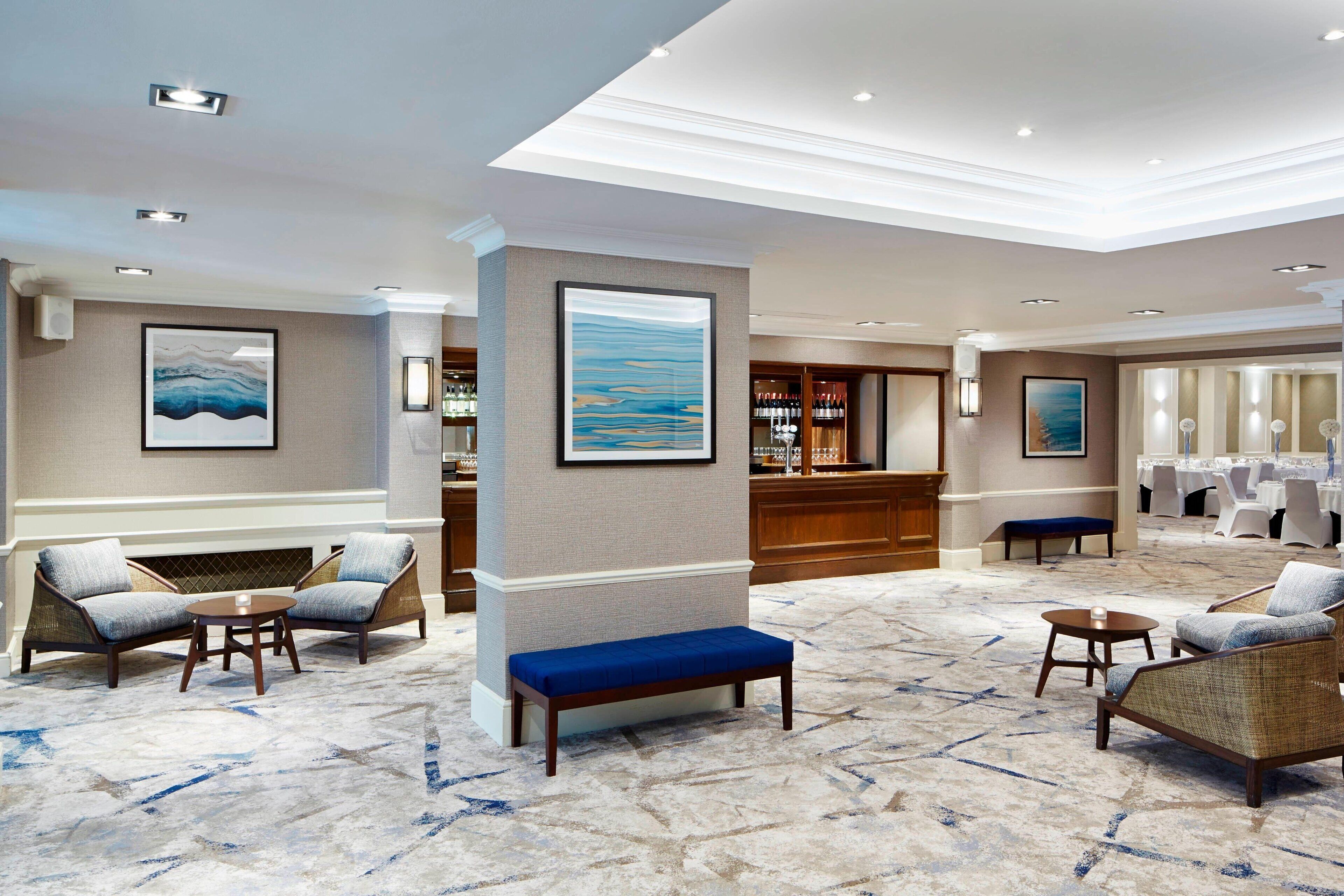 A hotel lobby with seating areas, a bar, and a conference room.