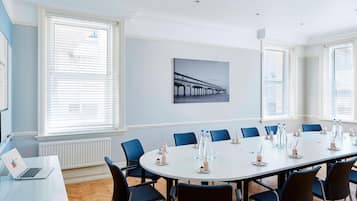 A conference room with a round table, blue chairs, and a laptop on a white table.