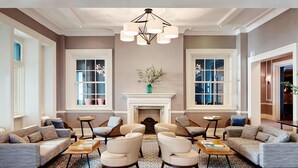 A spacious lobby with a patterned floor, a fireplace, and seating arrangements.