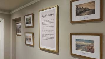 A wall with framed historical photographs and a descriptive text about Highcliffe Houses.