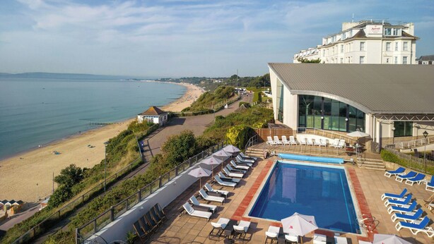 A hotel with a pool, beach view, and a Marriott logo.
