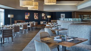 Un restaurante moderno con techos altos, iluminación colgante y una variedad de opciones de asientos.