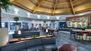 Een ruime lobby met een hoog houten plafond, een bar en zitgedeeltes.