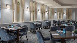 Un restaurante moderno con diferentes tipos de asientos, incluyendo mesas redondas y cabinas individuales.