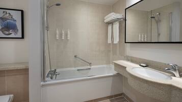 Un baño moderno con ducha de vidrio, bañera independiente y lavamanos de granito.