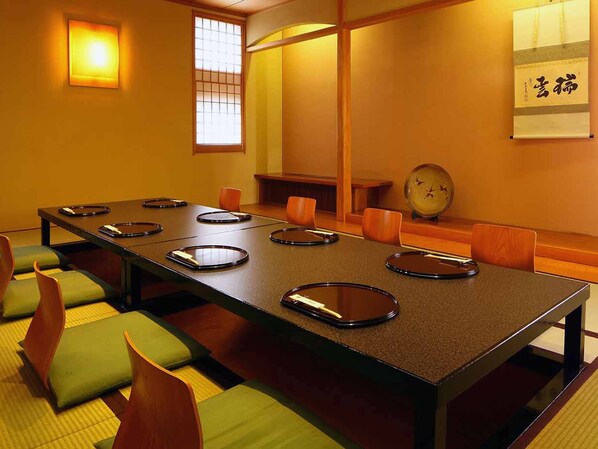 A conference room with a long table, green cushioned chairs, a clock, and a traditional Japanese sliding door.