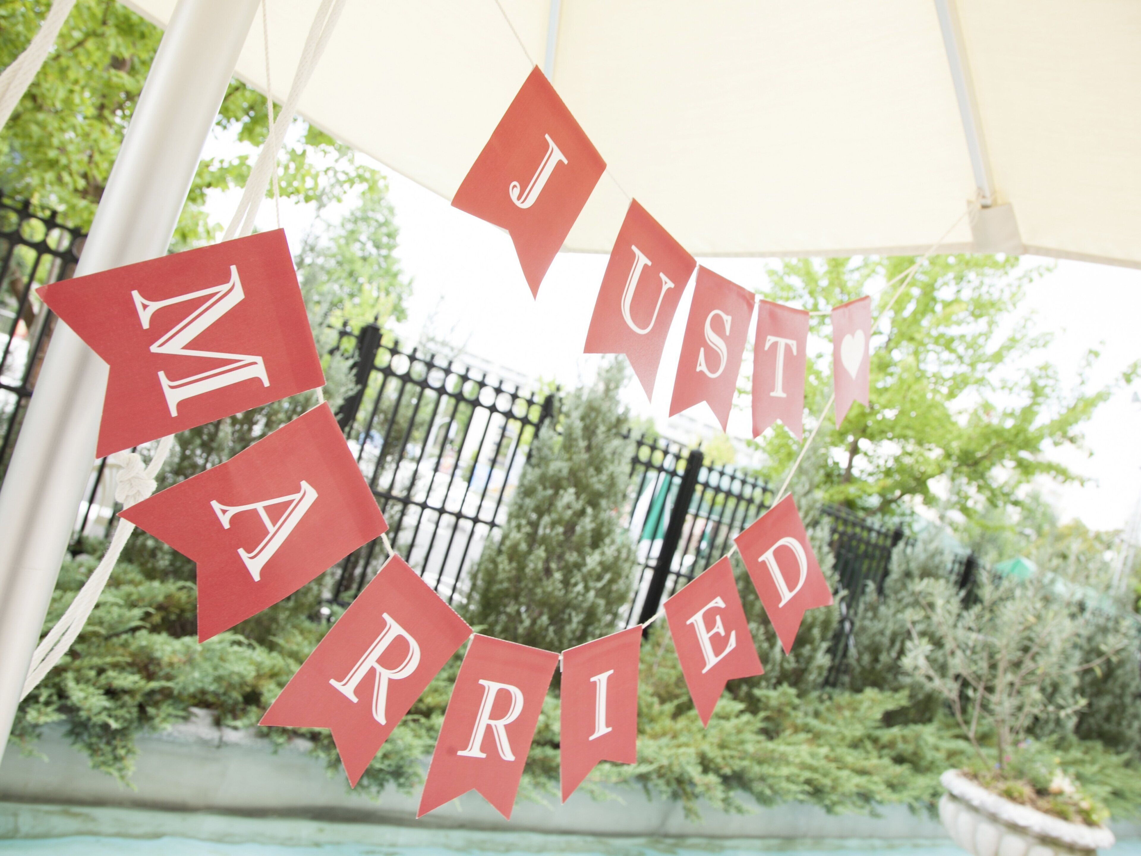Een hartvormige banner met de tekst 'I JUST MARRIED' die buiten hangt.