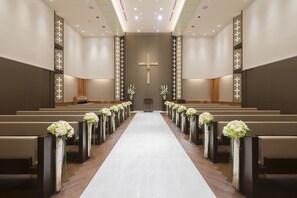 A church interior with pews aligned in rows, a central aisle, and a cross on the wall. - Hotel Nikko Tsukuba (Tsukuba)