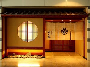 A traditional Japanese entrance with a circular window, a wooden bench, and a tiled floor. - Hotel Nikko Tsukuba (Tsukuba)