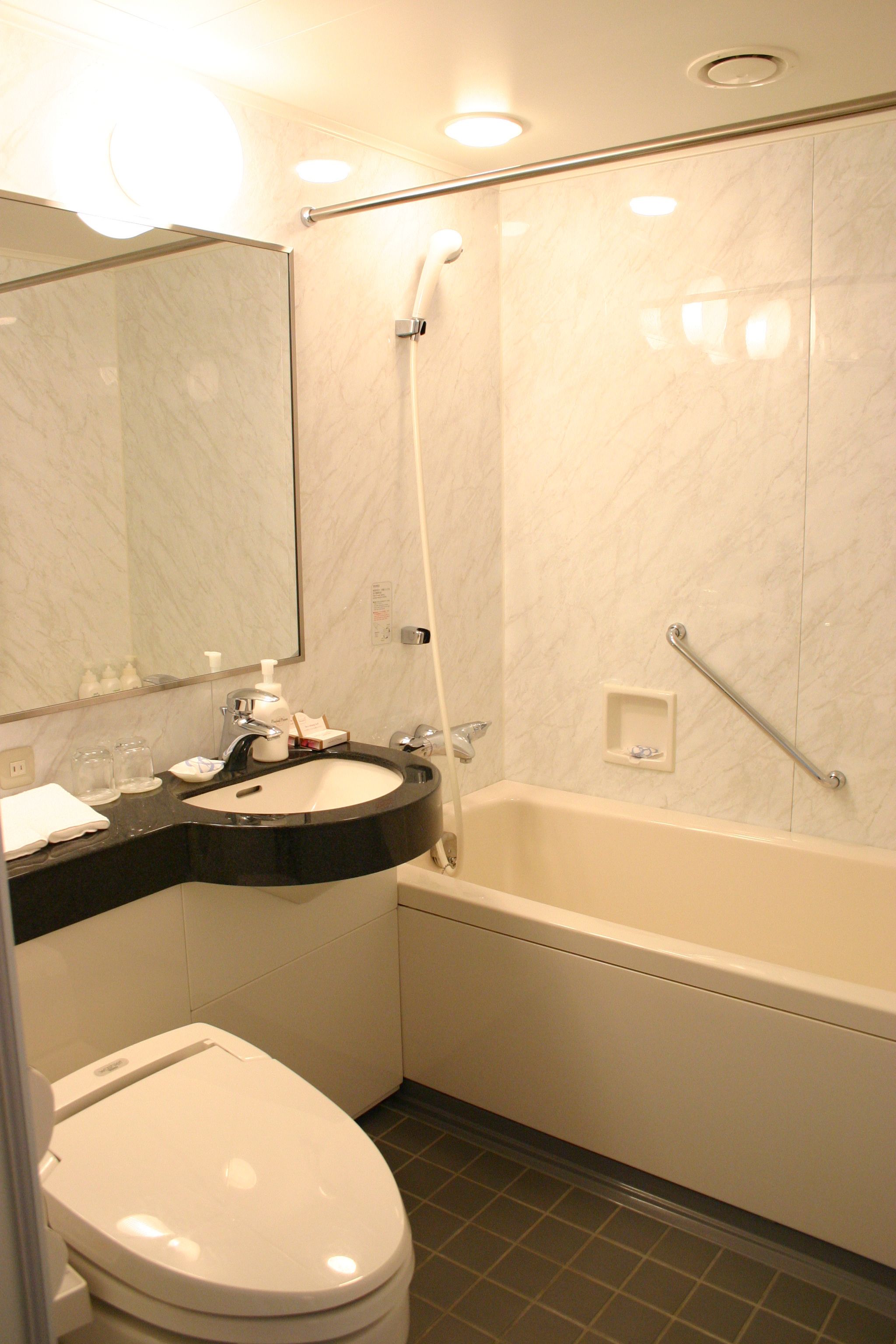 Une salle de bain équipée de toilettes, d’un lavabo, d’un miroir et d’une baignoire.