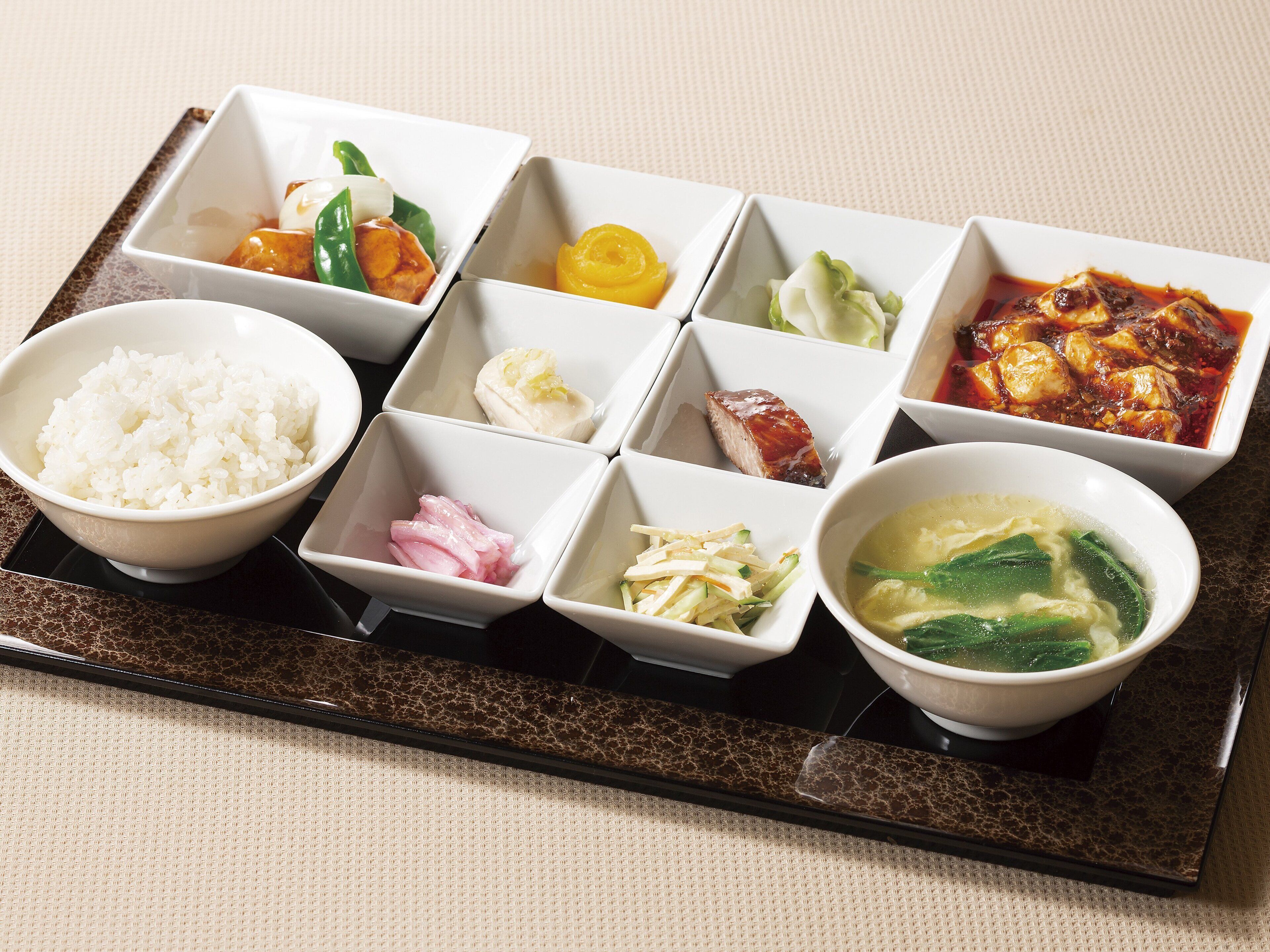 A tray with various dishes including rice, vegetables, and soup.