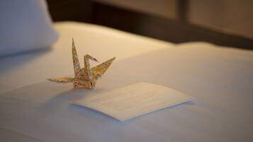 Una cama bien hecha con una grulla de origami doblada sobre un papel.