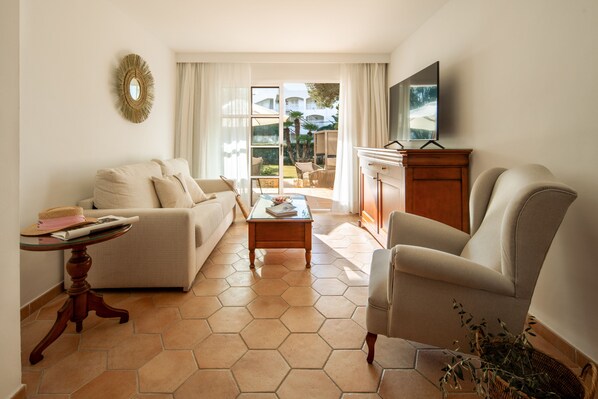 A living room with a sofa, armchair, coffee table, and a TV on a wooden cabinet.