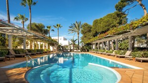A swimming pool with a circular design, surrounded by lounge chairs and palm trees. - Melia Cala d'Or Boutique Hotel (Santanyi)