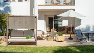 Una zona exterior moderna amb seients, un sofà, cadires i un parasol gran.