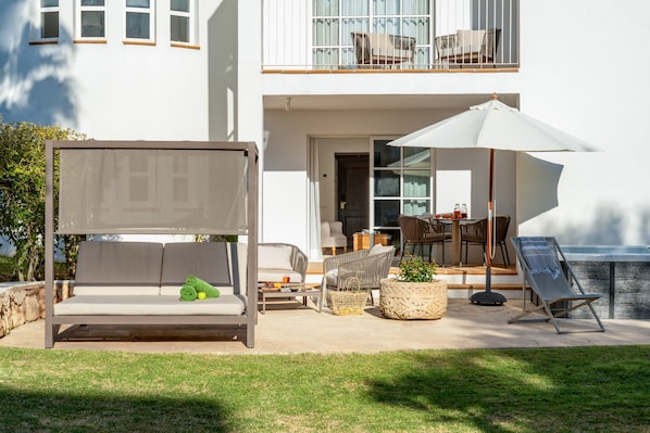 A modern outdoor seating area with a sofa, chairs, and a large umbrella.