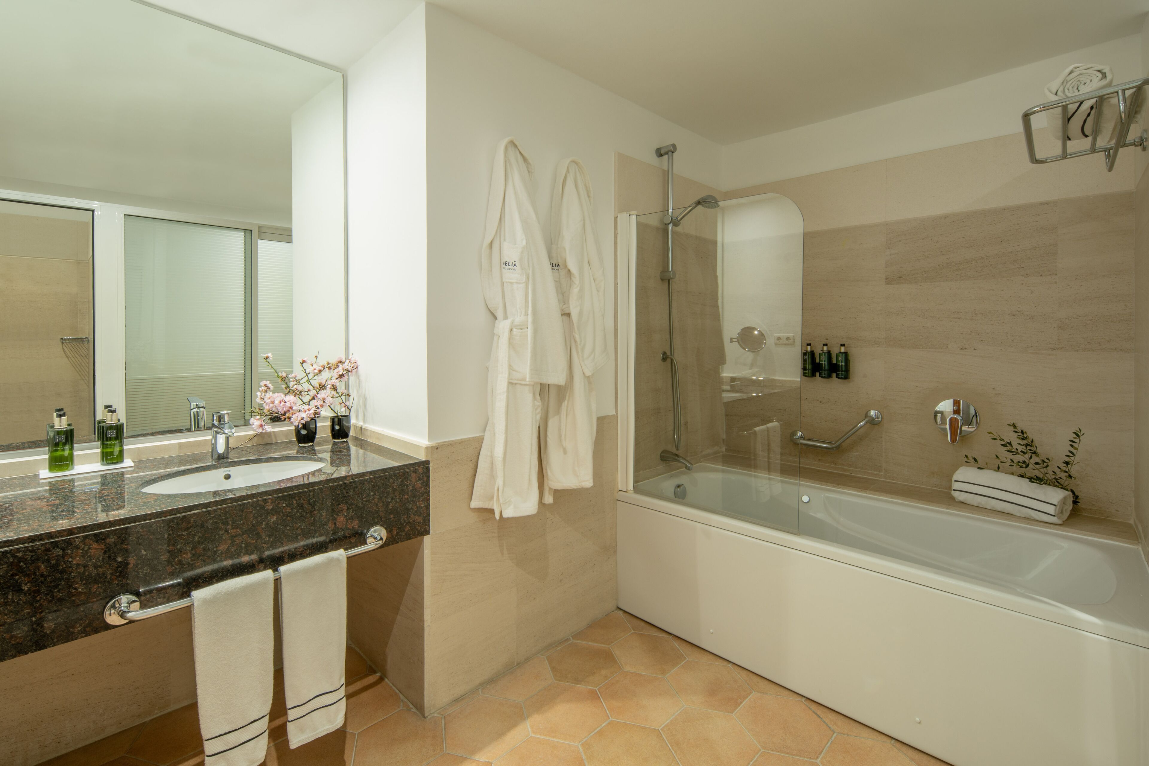 Un baño moderno con ducha envuelta en vidrio, una bañera grande y una encimera de granito con lavamanos.