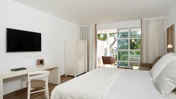 Une chambre d’hôtel moderne dotée d’un grand lit, d’un bureau avec une chaise, d’une télévision et d’une porte-fenêtre coulissante donnant sur un espace extérieur.