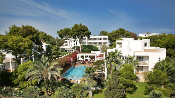 A resort with a swimming pool surrounded by lush greenery and white buildings. - Melia Cala d'Or Boutique Hotel (Santanyi)