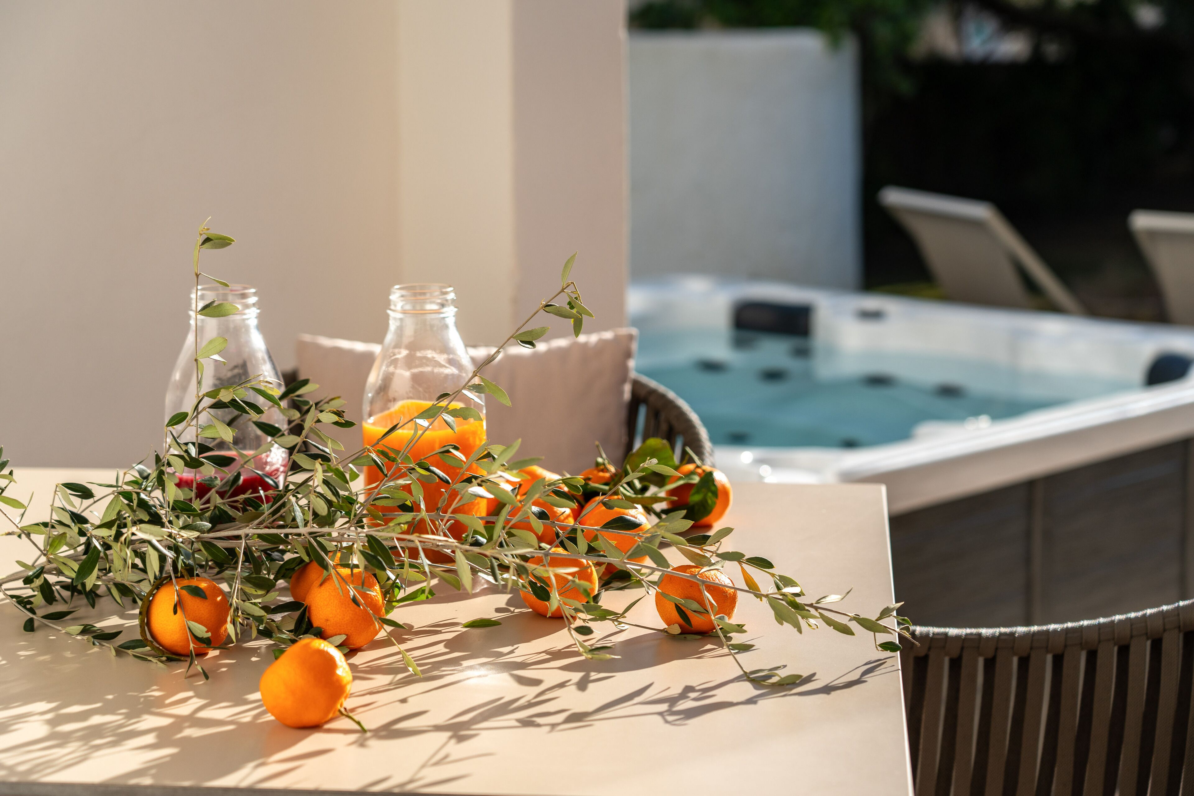 Een tafel met sinaasappels en takken, een hottub en een stoel op de achtergrond.