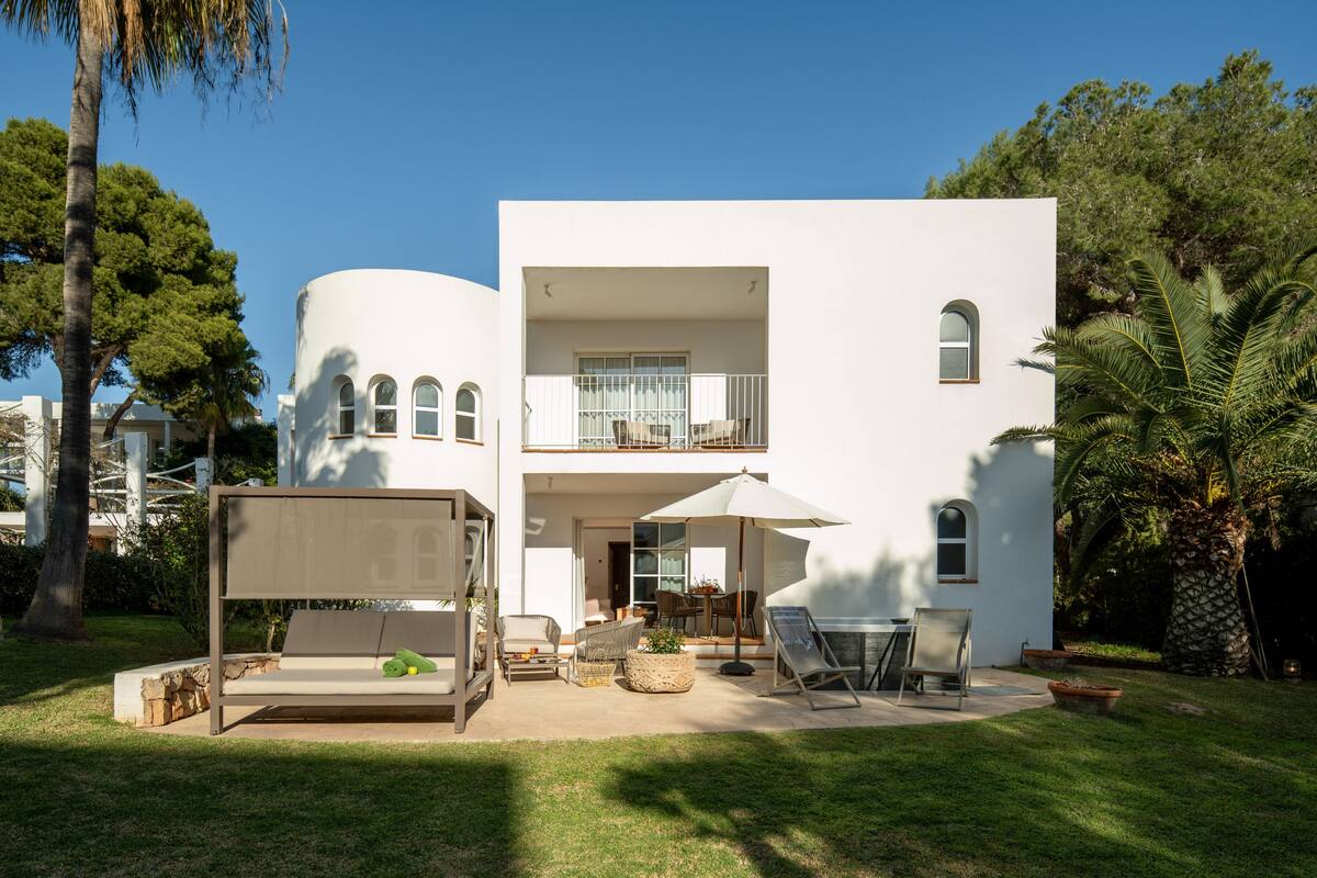 A modern two-story house with a patio area featuring outdoor furniture and a grill.