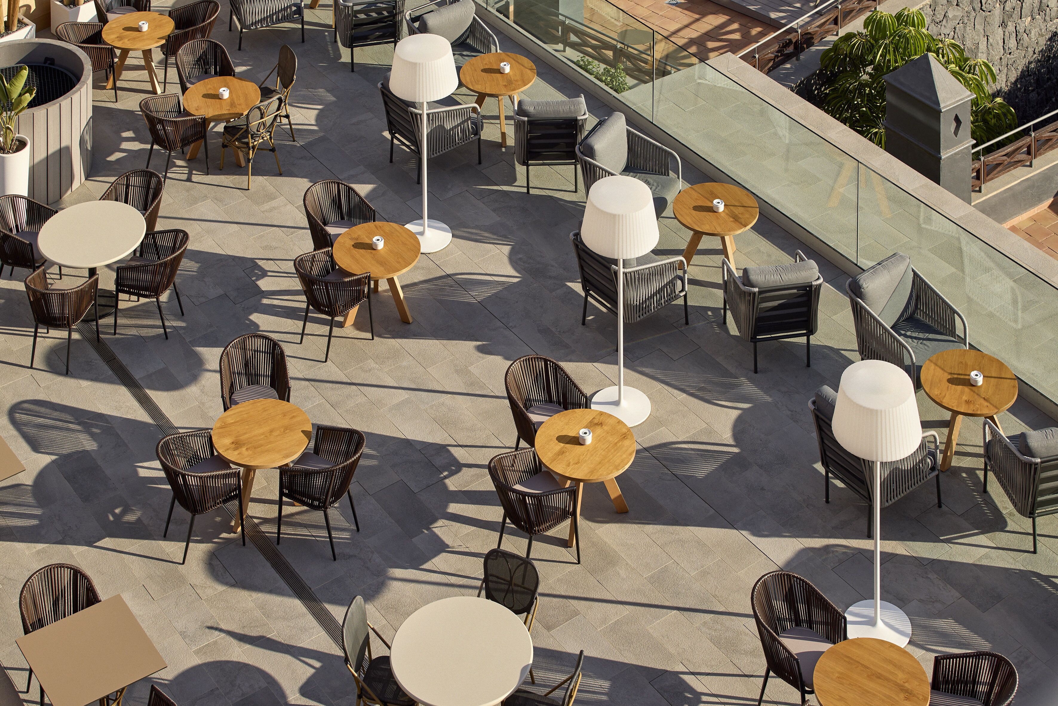 An outdoor patio with round tables and wicker chairs, arranged in a spacious layout with a clear view of the surrounding area.