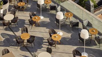 An outdoor patio with round tables and wicker chairs, arranged in a spacious layout with a clear view of the surrounding area.